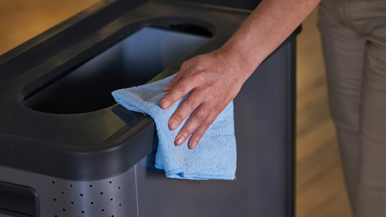 A person cleaning a bin using the Microfibre Light Commercial Cloth